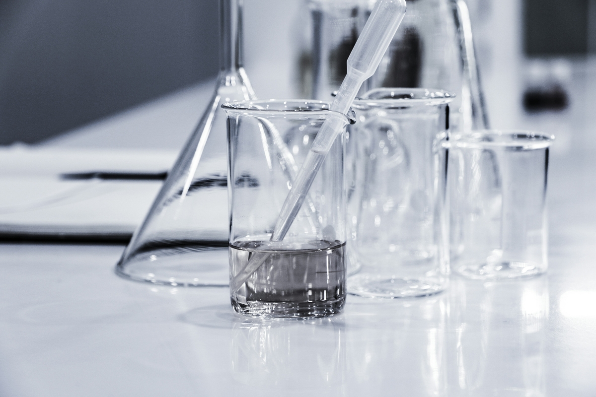 Beaker with pipette and assorted glass labware on a white lab bench
