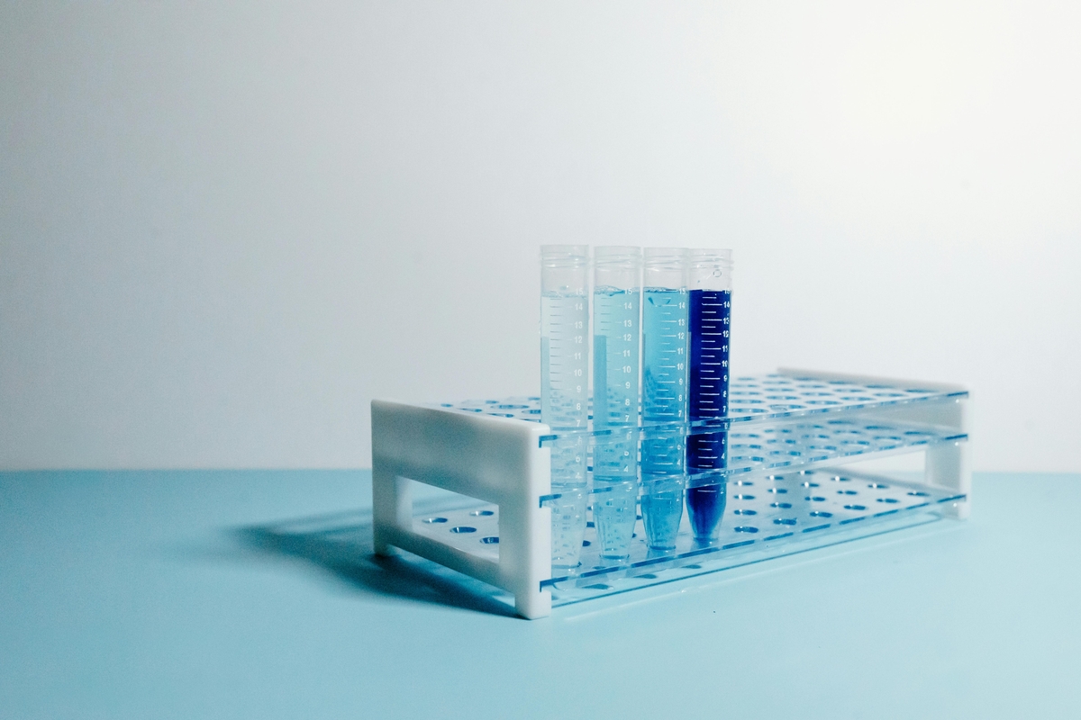 Transparent test tubes with blue liquid placed in a metal rack on a clean laboratory surface